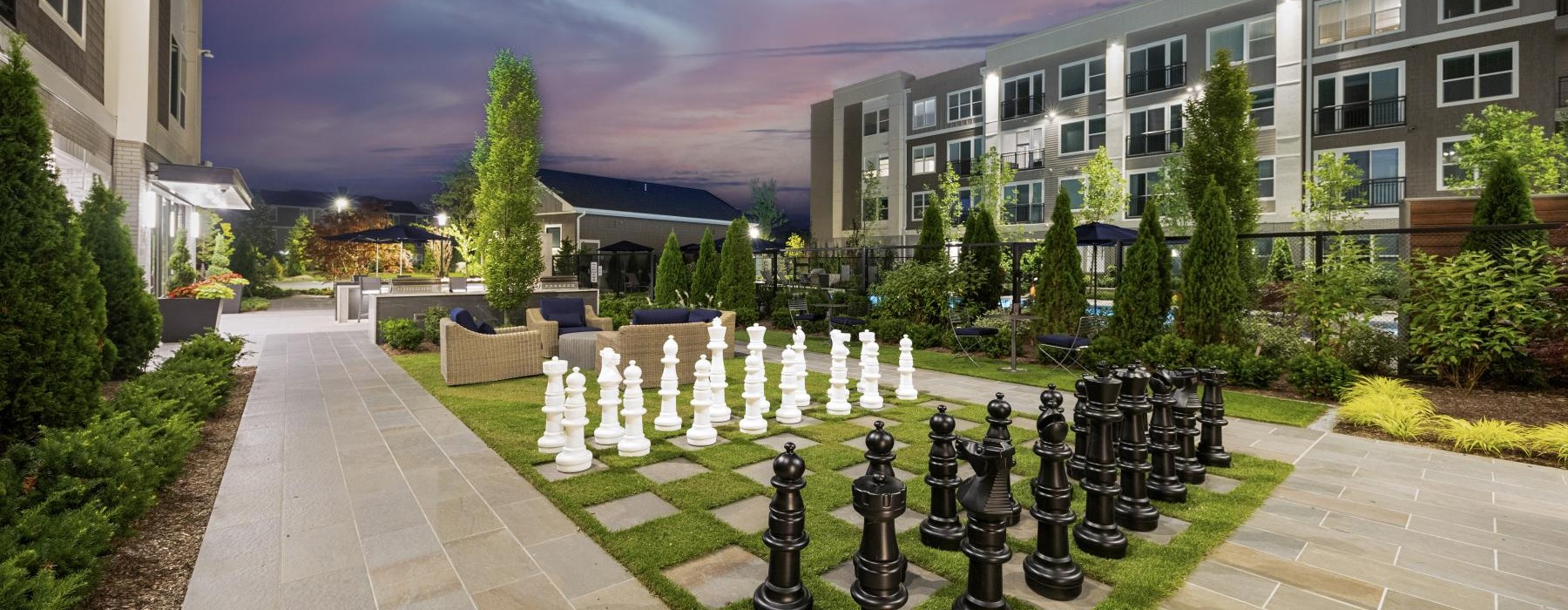a courtyard with a chess board and buildings in the background